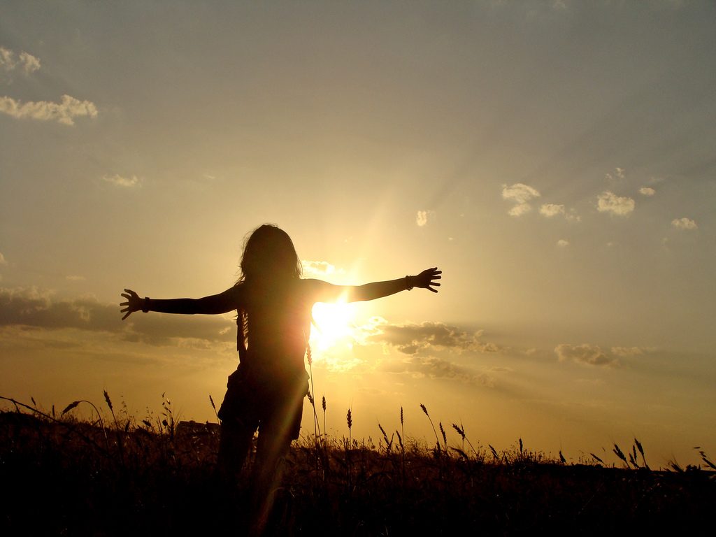 woman with open arms in open field