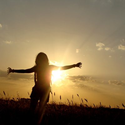 woman with open arms in open field